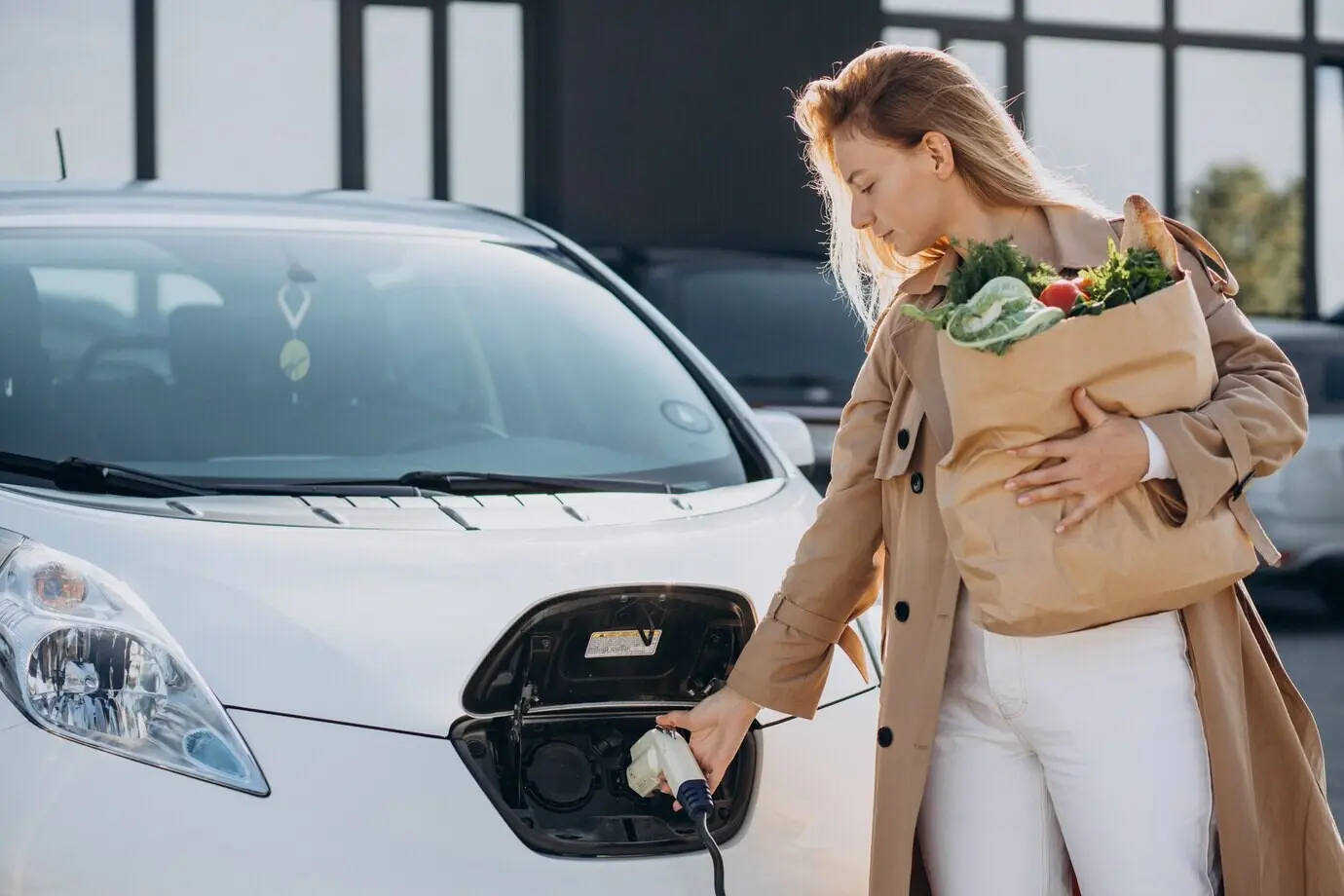 Woman with grocery bags charging an electric car