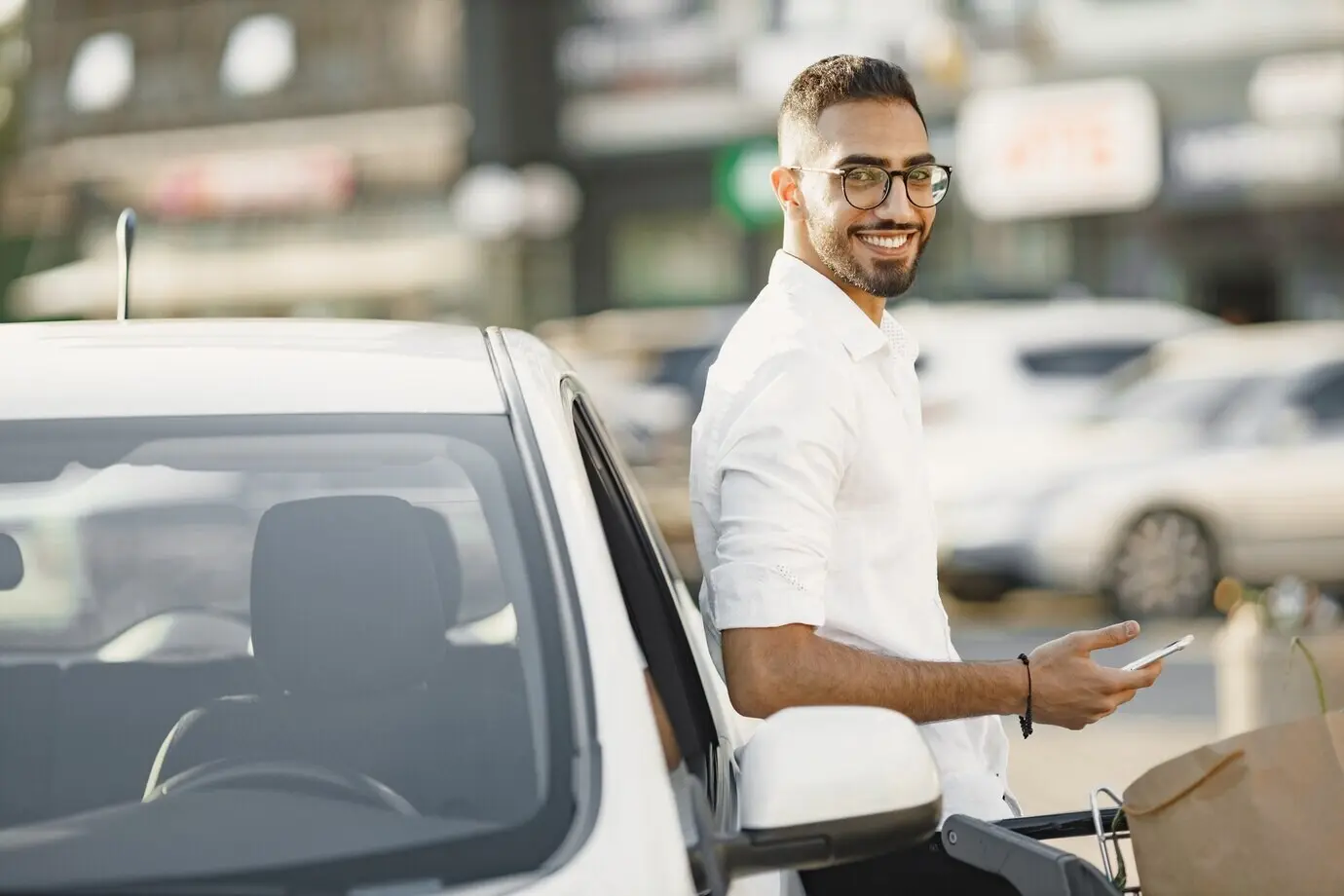 An Arab man uses a smartphone while waiting for the battery to charge in the car. Eco awareness.